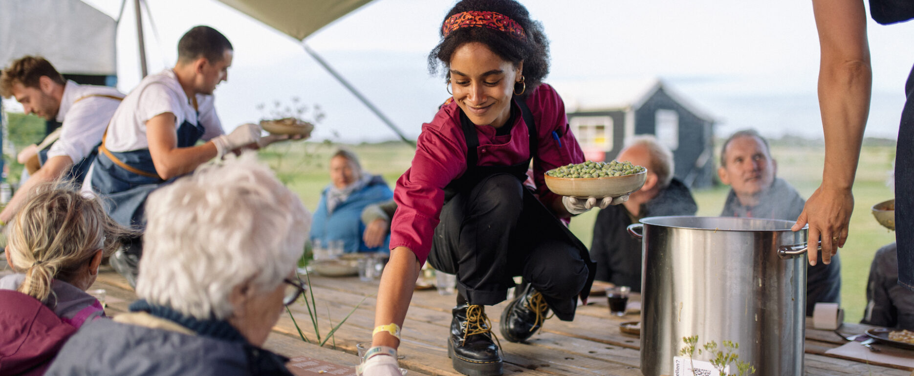 Chef serveert plantaardige maaltijd op tafel buiten op een festival.